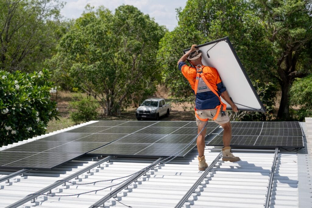 EcoT echSolar InstallPhotos Eco Tech Electrical worker carrying a solar panel across the roof during a solar installation in Darwin, NT